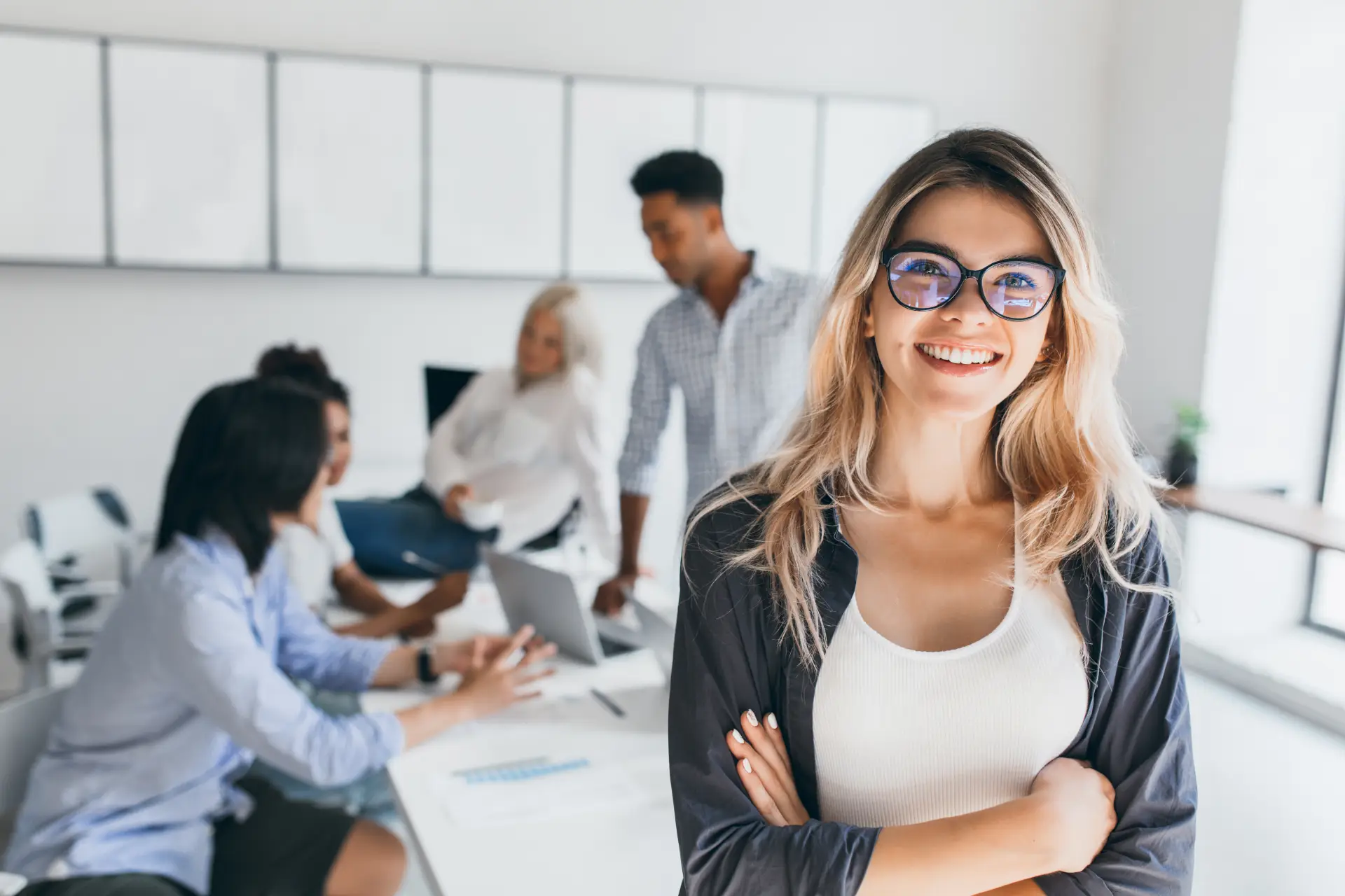 Team in conference room - female team member with eyeglasses in foreground smiling